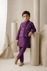 Young boy wearing a royal purple premium raw silk kurta pajama set with a star-embellished waistcoat and gold khussas for festive weddings.