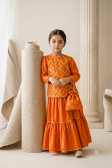 Young girl wearing a marigold orange katan silk gota work kurti and tiered flared sharara with a matching potli bag and gold khussas.